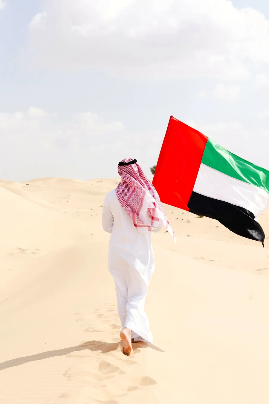 Emirati man carrying the UAE flag across the desert near Al Ain