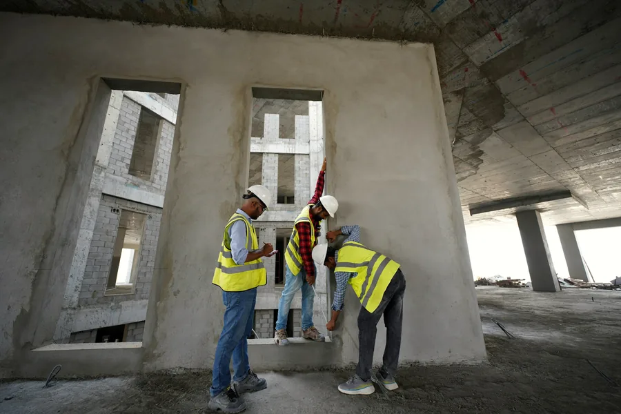 Engineers measuring a concrete wall on a building site